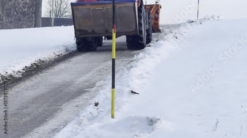 tractor plowing snow on rural road in winter