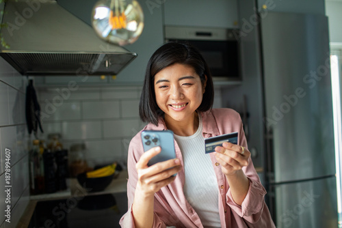 Photos Smiling woman making online payment at home kitchen