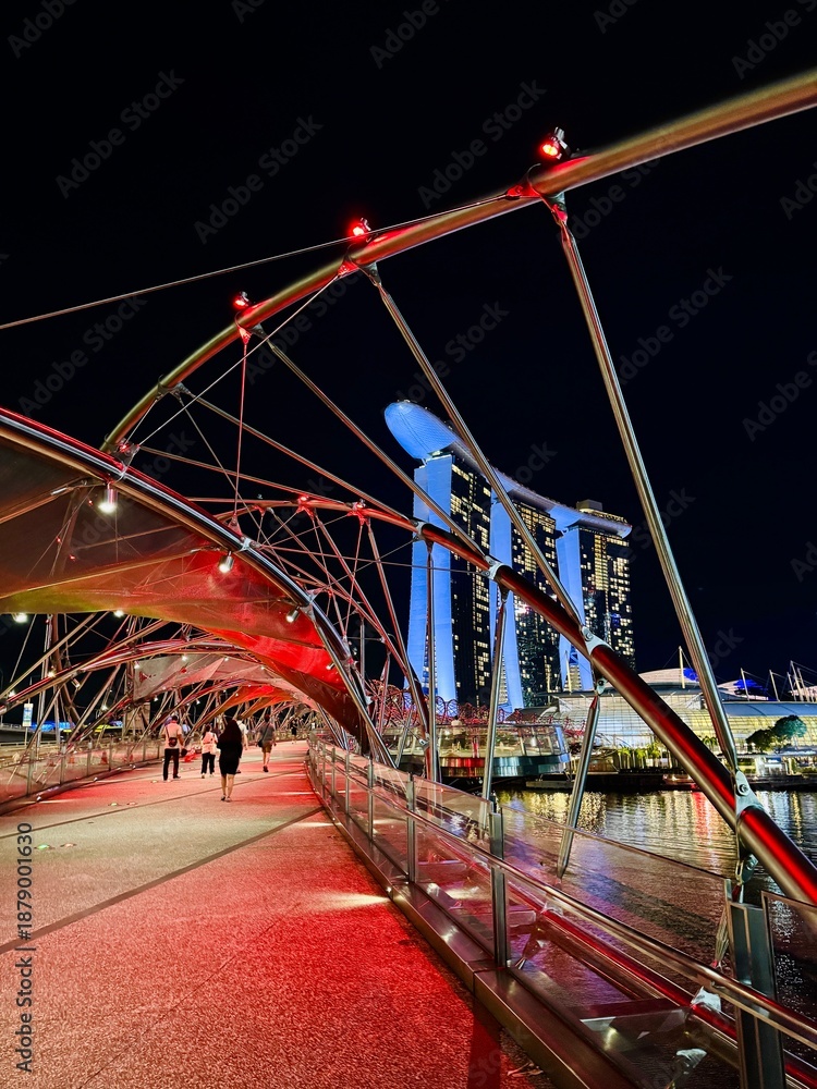 Obraz premium Illuminated bridge over marina bay, Vibrant nighttime scene featuring illuminated bridge and bustling waterfront promenade