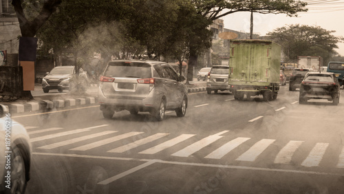 Foto Busy urban traffic with cars and a truck driving through thick air pollution and smog on a city road