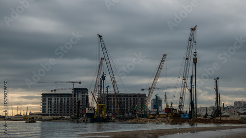 Building construction on the coast with cranes, new development near the sea.