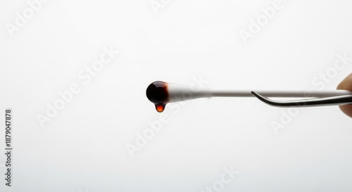 Medical Cotton Swab Held by Forceps Dripping Dark Antiseptic Solution (Iodine) on White, Symbolizing Clinical Hygiene and Wound Disinfection Procedures.