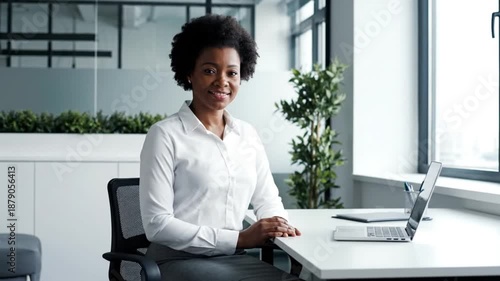 Confident businesswoman sitting at modern office desk with laptop