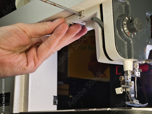 Quadro em tela Close-up shot of a person's hand setting up or repairing an older, classic sewing machine