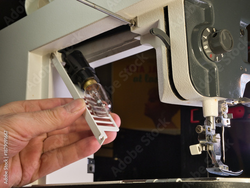  Close-up shot of a person's hand setting up or repairing an older, classic sewing machine. Focus on the mechanism, needle, and presser foot area, highlighting DIY skills.