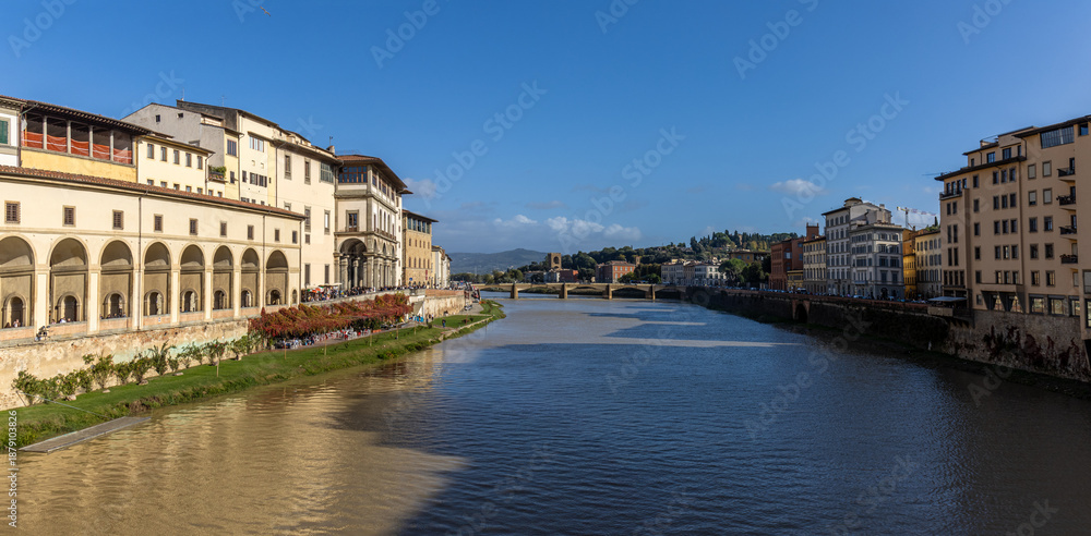 Fototapeta premium Panoramic view of the Arno River flowing through Florence with its historic architecture. Florence, Italy