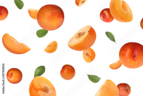 Fresh plums and green leaves flying in air on white background