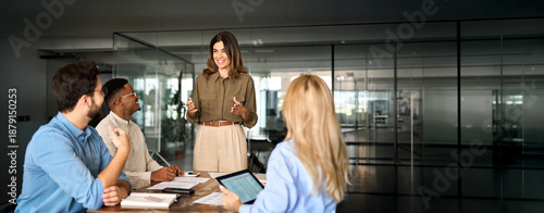 Happy middle aged business woman executive ceo leader discussing project management planning strategy working with diverse colleagues company team at office corporate board group meeting.