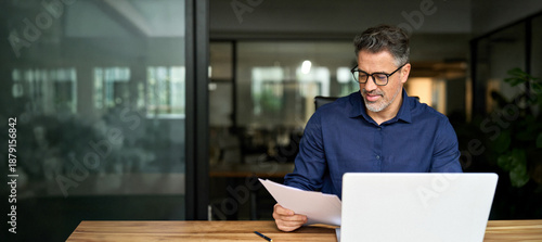 Konstfotografi 50 years old man executive manager or business owner reading paper working on computer