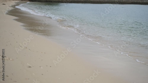 Soft ocean waves washing onto a clean sandy beach with clear water