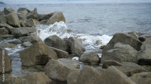Strong sea waves hitting large rocks on the coast creating splashes and motion