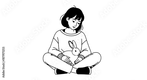 Young girl sitting cross-legged holding a pet rabbit in her lap.
