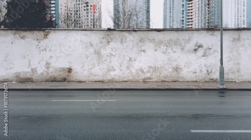 City street with long concrete wall covered in white plaster featuring copy space and mockup   