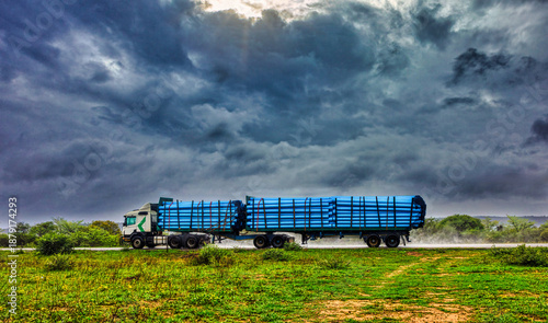 Truck driving in a severe rainstorm on a remote highway hauls pipes on open road
