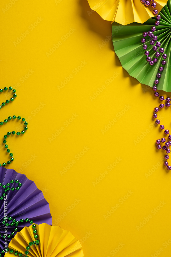 Obraz premium Vibrant vertical Mardi Gras themed scene features purple, green, and gold fans and bead garlands arranged on a bold yellow background, conveying festive energy and a lively greeting for events