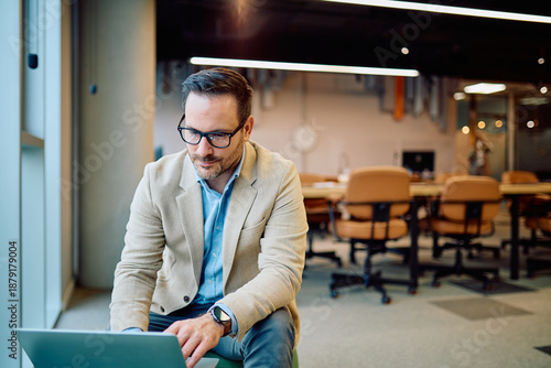 Fotografie Businessman in glasses focused on his laptop, working remotely from a contempora