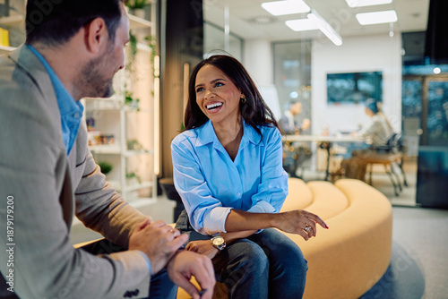 Two diverse business professionals sharing ideas and communicating happily in a modern office lounge area