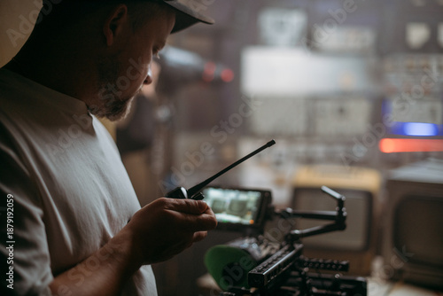 Director of photography with a camera in his hands on the set. Professional videographer at work on filming a movie, commercial or TV series. Filming process indoors, studio