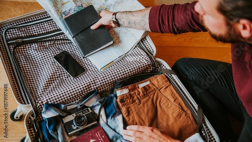 Tableau sur toile Man packing suitcase with clothes, map, and camera