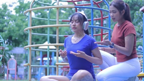 Two women sit peacefully in a colorful playground structure, practicing meditation and finding inner calm amidst the urban landscape