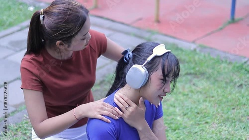 A gentle scene unfolds outdoors as one young woman offers a comforting embrace and reassuring touch to another who appears to be experiencing a