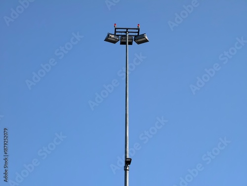 minimalist floodlight pole under bright sky, single tall floodlight mast with lamp cluster