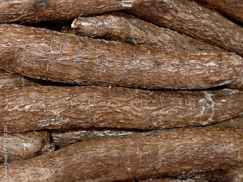 marketplace with fresh rustic cassava tubers, vendor prepares raw cassava roots for shipment