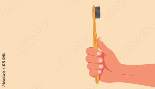 Hand holding a bamboo toothbrush with black bristles on beige background  