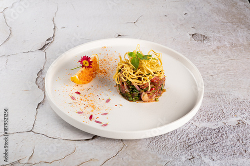 Minimalist Spicy Noodle Dish with Herbs and Citrus Garnish on White Plate