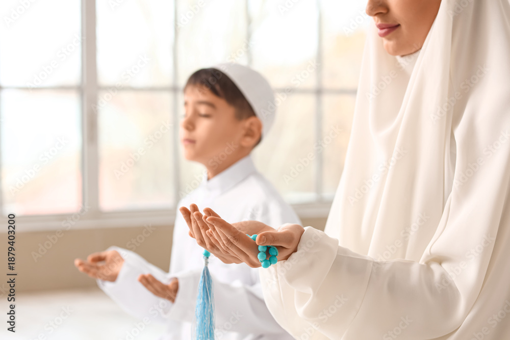 Obraz premium Muslim mother with her son praying in room, closeup. Ramadan celebration