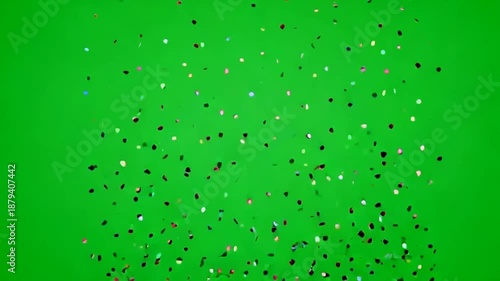 Colorful confetti particles falling on green background for celebration