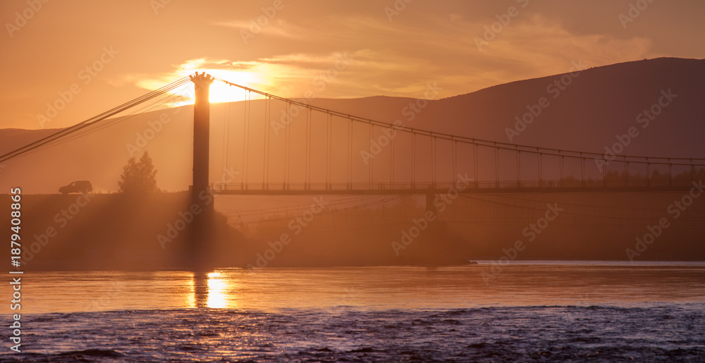Obraz premium Bridge over the river against the backdrop of a bright sunset, summer travel