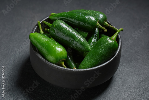 Tableau sur toile Bowl with green jalapeno peppers on black background, closeup
