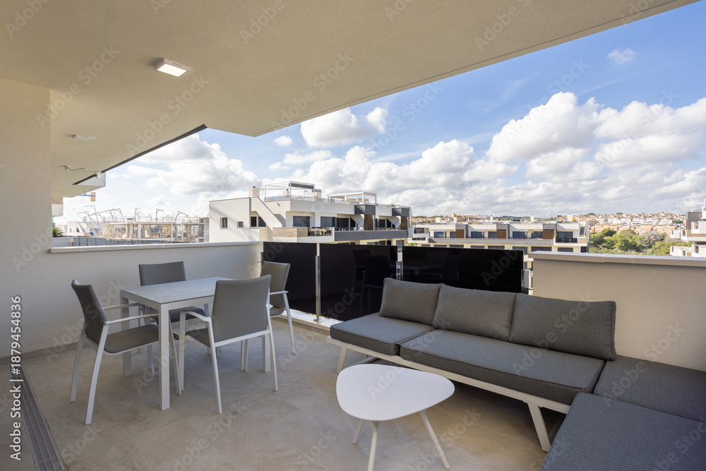 Fototapeta premium Spacious terrace with outdoor seating and city view in modern apartment complex