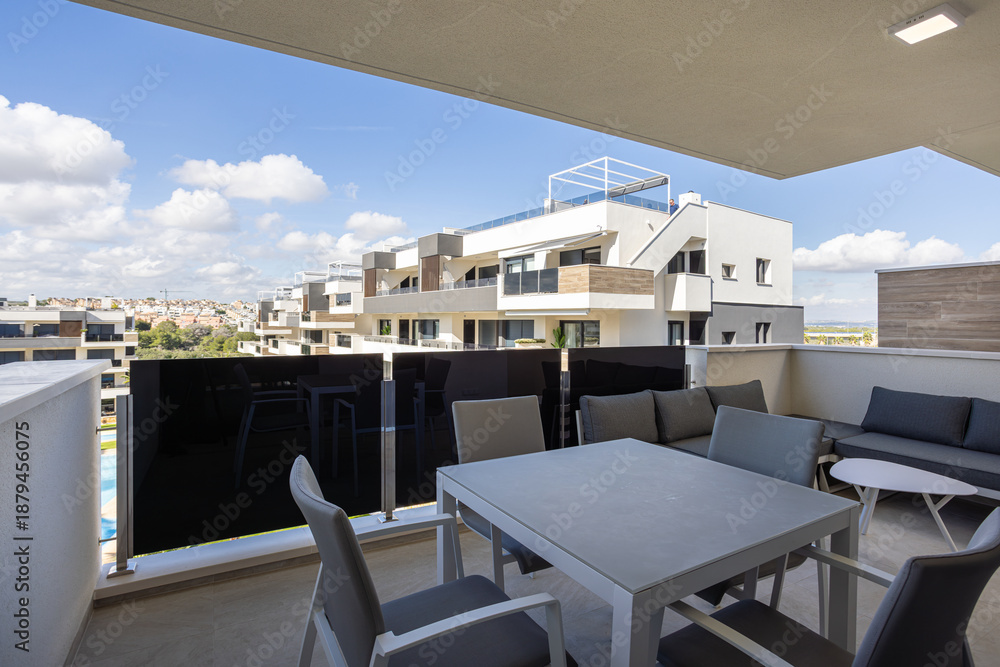 Obraz premium Modern apartment terrace with gray furniture and scenic city views