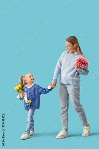 Little girl with her mother and bouquets of tulips on blue background. International Women's Day