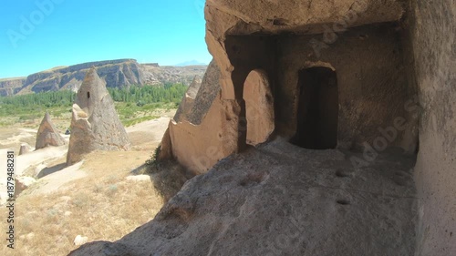 Fairy chimneys and ancient cave monasteries carved into volcanic rock landscapes of Cappadocia. Historic hoodoo formations reveal stone dwellings spires valleys seen from curious traveler view.