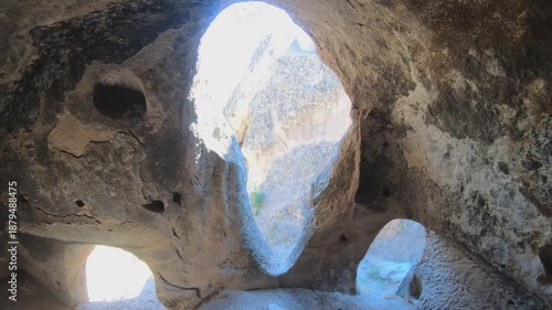 Fairy chimneys and ancient cave monasteries carved into volcanic rock landscapes of Cappadocia. Historic hoodoo formations reveal stone dwellings spires valleys seen from curious traveler view.