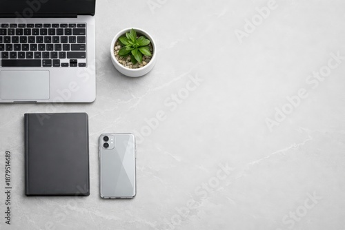 A modern workspace setup with a laptop, notebook, smartphone, and a small potted plant, symbolizing productivity, organization, and tech-savvy business environments. Perfect for office, work, or digit