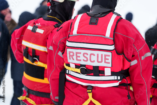 Back view of rescue worker in red safety vest with harness during emergency operation
