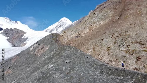 A girl walks along a mountain range. There are snowy mountains in the background. Active recreation