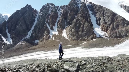 A girl walks along a mountain range. There are snowy mountains in the background. Active recreation