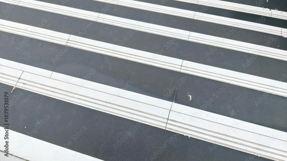 Obraz premium Close up zebra crossing road markings with white lines on dark asphalt. Perfect for traffic safety, transportation, urban life, background design, education, and editorial content. Ideal for designers