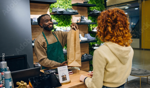 Young Caucasian man Handing Shopping Bag to Young women in a store