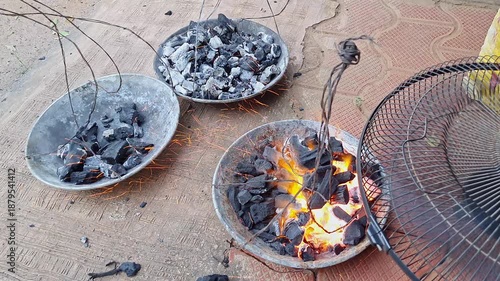 closeup of burning charcoal and benzoin or frankincense in a rustic pan with fan wind