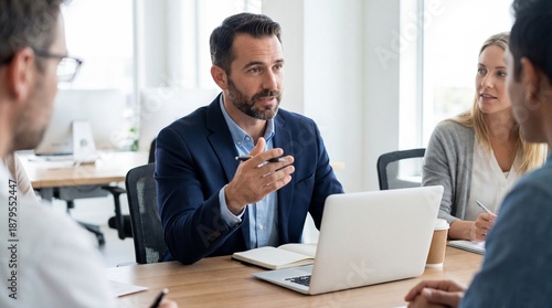 Wallpaper Mural A diverse group of professionals in a modern meeting room, engaged in a productive discussion around a laptop and notebook, fostering collaboration and strategy. Torontodigital.ca