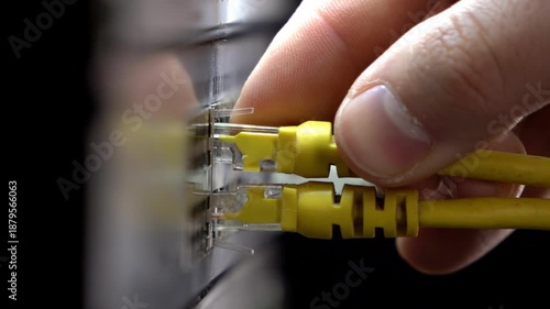 Close-up of a hand plugging an ethernet cable into a network switch in a server rack, data center maintenance and IT connection concept with shallow depth of field.