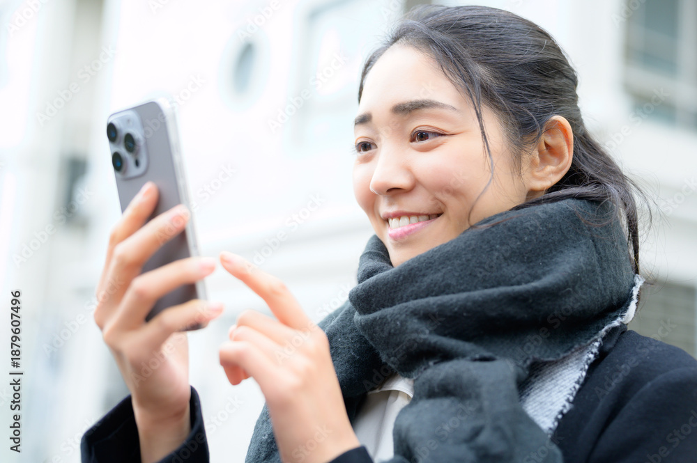 Fototapeta premium マフラーをしてスマホを使用する日本人女性