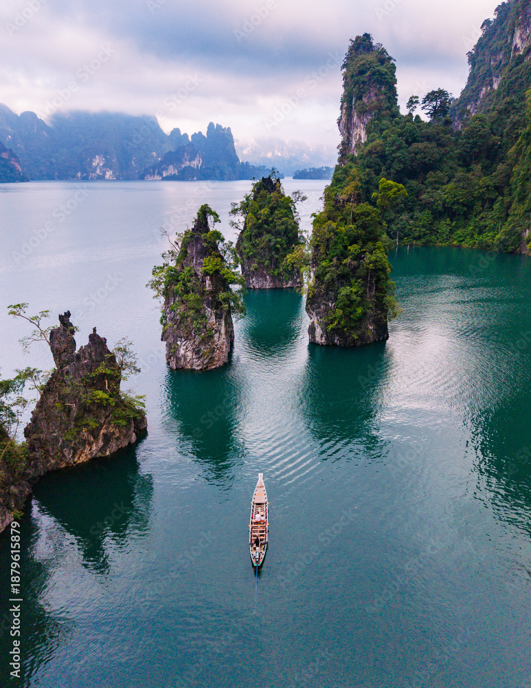 Naklejka premium Serene boat ride through the stunning landscape of Cheow Lan Lake in Khao Sok Thailand