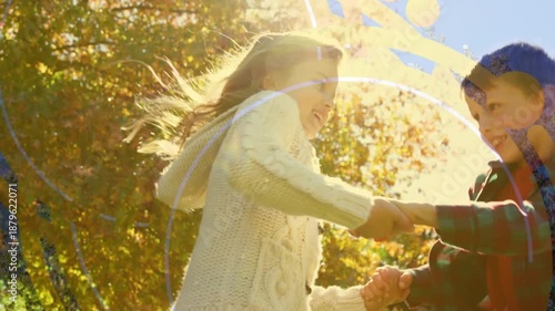 Two children holding hands and turning in a park
